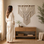Woman standing next to large handmade macramé wall hanging